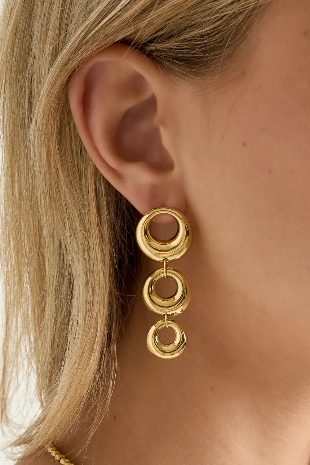 Model draagt gouden Dangle statement oorbellen met drie ronde schakels – Mysa Lifestyle