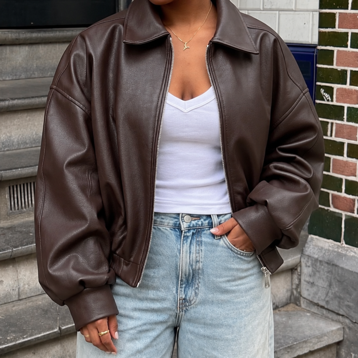 Vrouw draagt Jasje Nova in bruine leather look met wit topje en jeans
