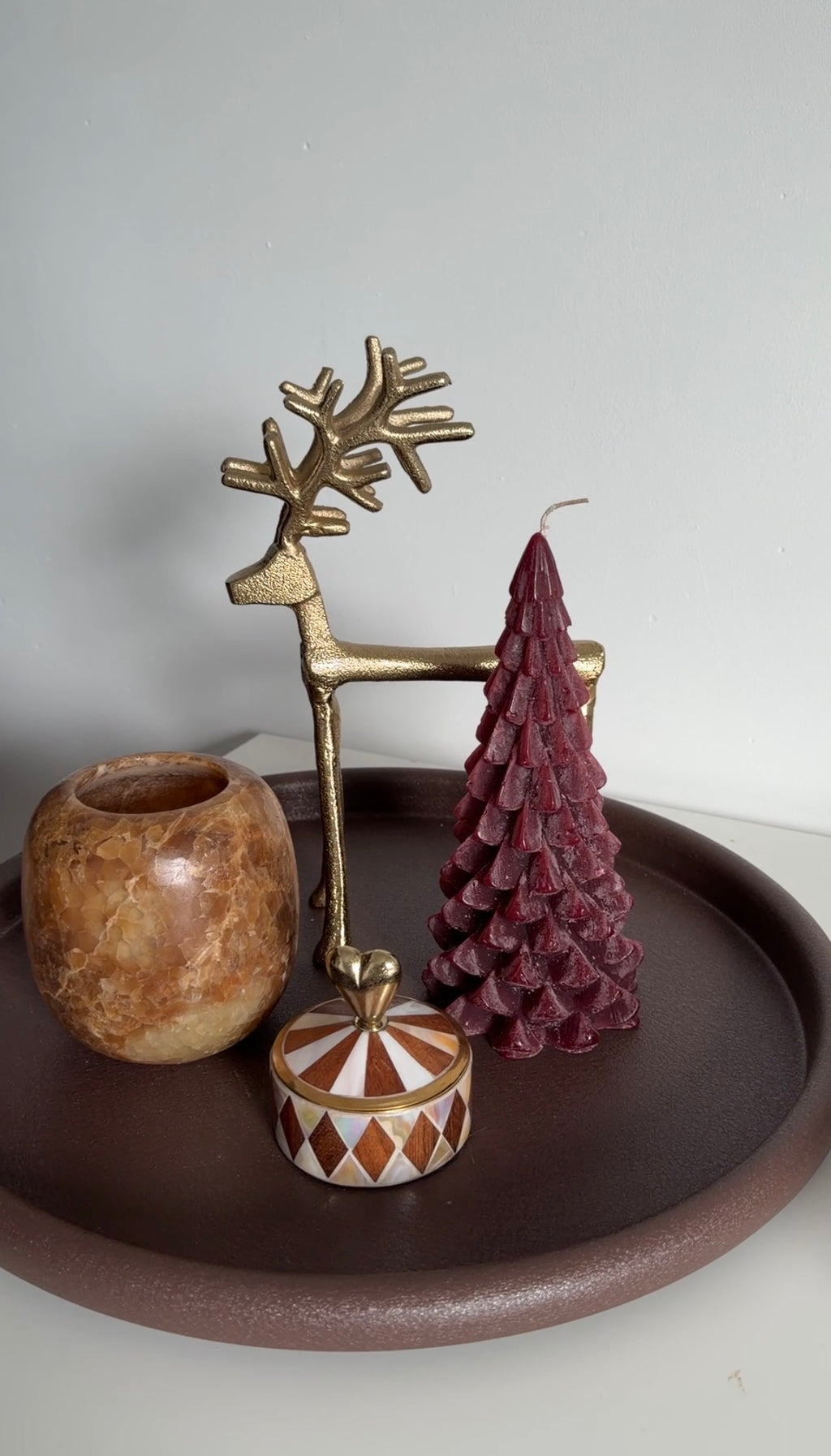 Decoratieve wijnrode kerstboomkaars gecombineerd met gouden rendier en sfeervolle kerstdecoratie