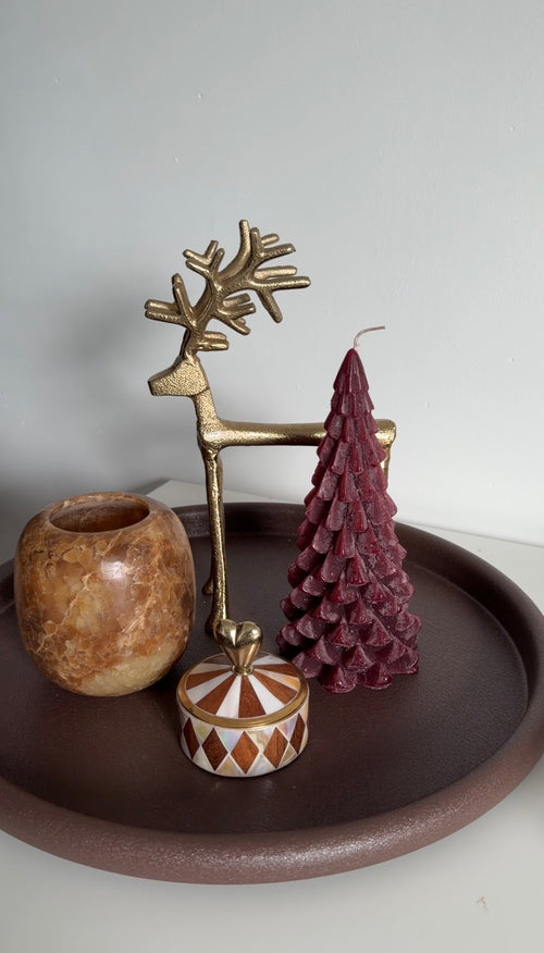 Decoratieve wijnrode kerstboomkaars gecombineerd met gouden rendier en sfeervolle kerstdecoratie
