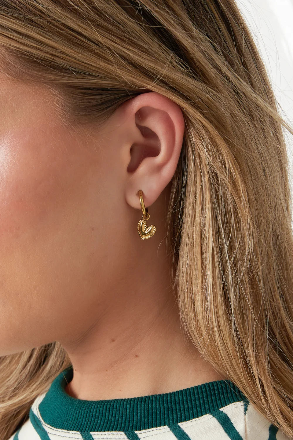 Model draagt gouden Dangle Heart oorbellen met hangende hartjes – Mysa Lifestyle